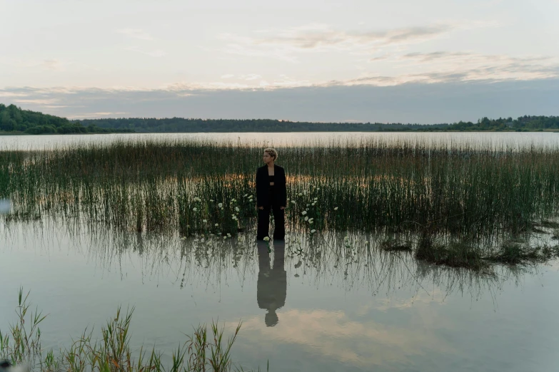 a man standing in the middle of water with tall grass