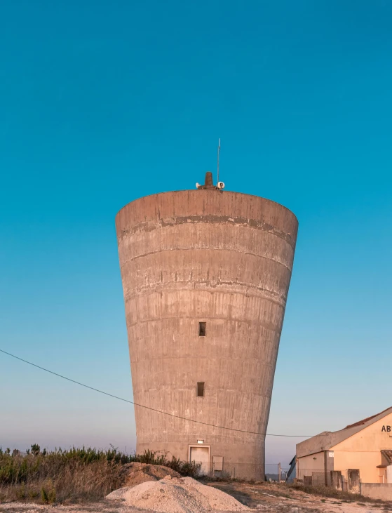 a cement silo next to a barn in the desert