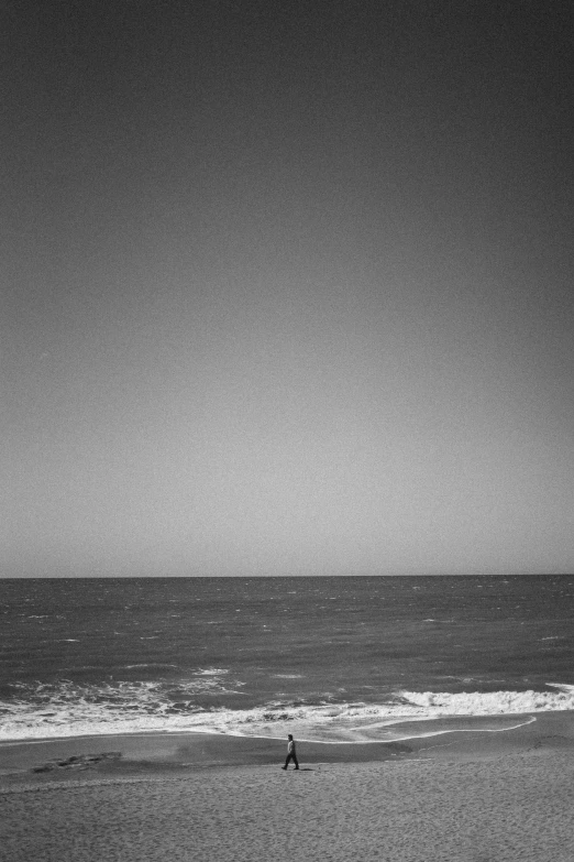 black and white po of a person flying kite at beach