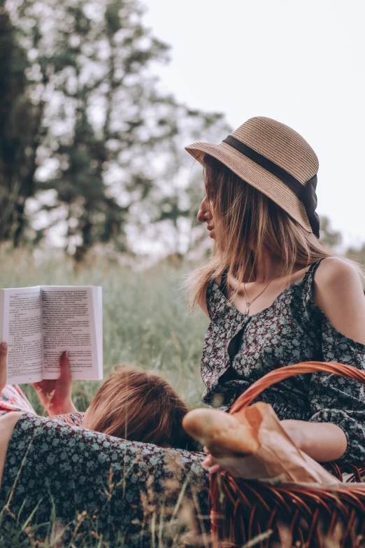 two young women sitting in a field reading books