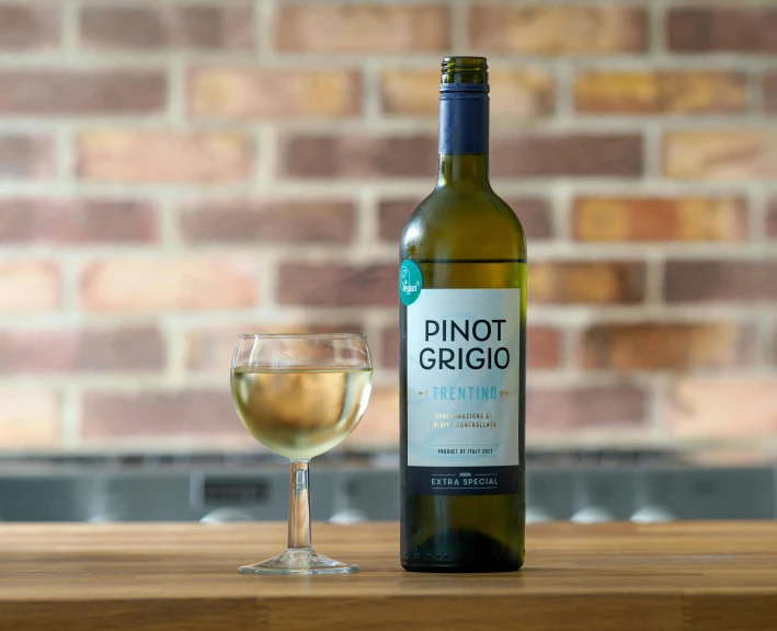 a wine glass next to a bottle of white wine on a wooden table