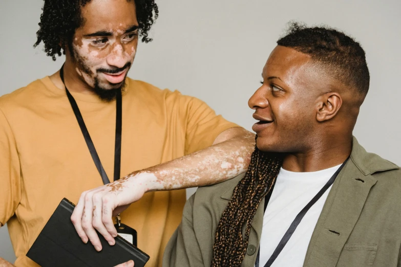 a man touching his face while another person holds an object near him