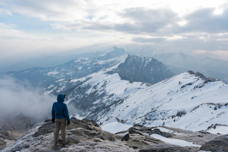 a man standing on a mountain looking out at the view