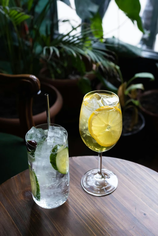 a glass with two slices of lemon next to an alcoholic drink