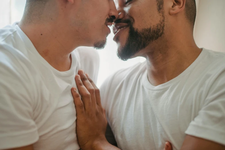 two people are kissing, one man is holding the other