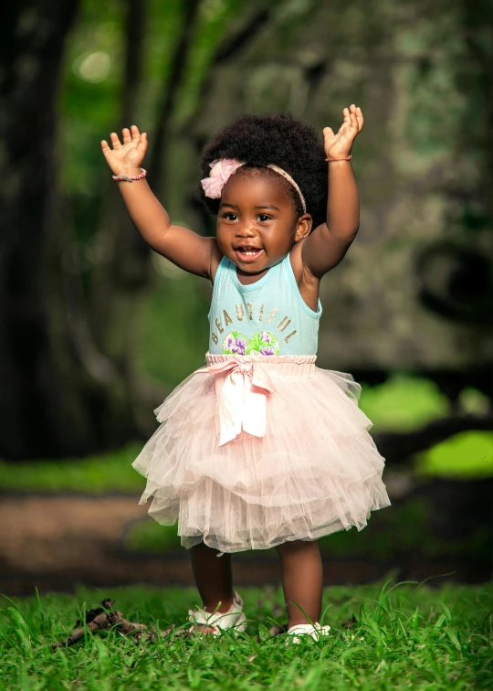 a young african girl wearing a princess dress while standing on the grass