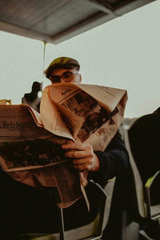 a man sitting on top of a boat reading a newspaper