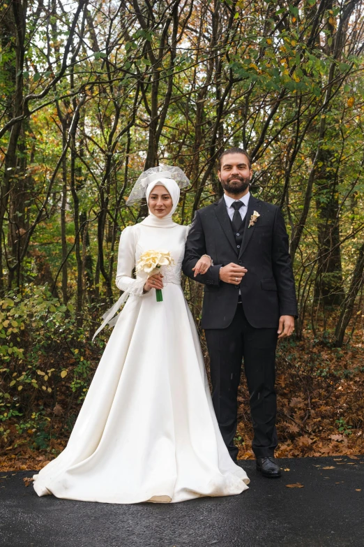 a man in a suit and woman in a white wedding gown walking down the road