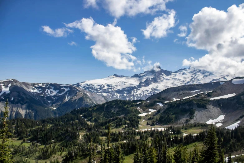 some snow mountains with trees and clouds