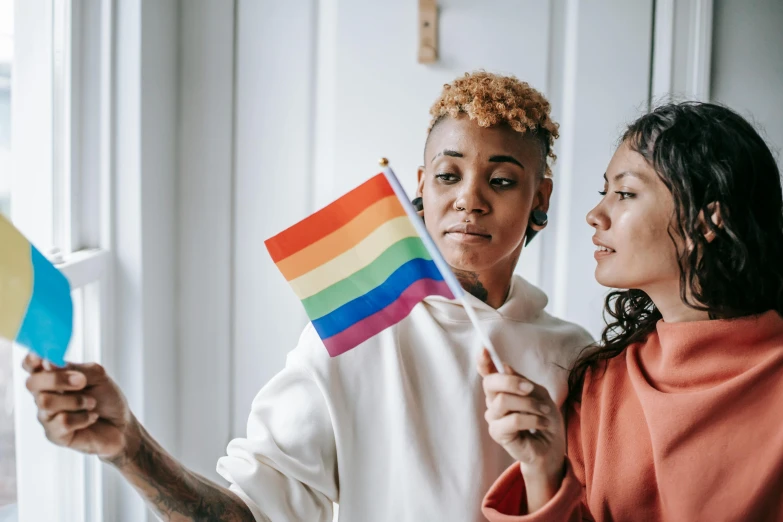 two young ladies are holding an american and a rainbow - flag