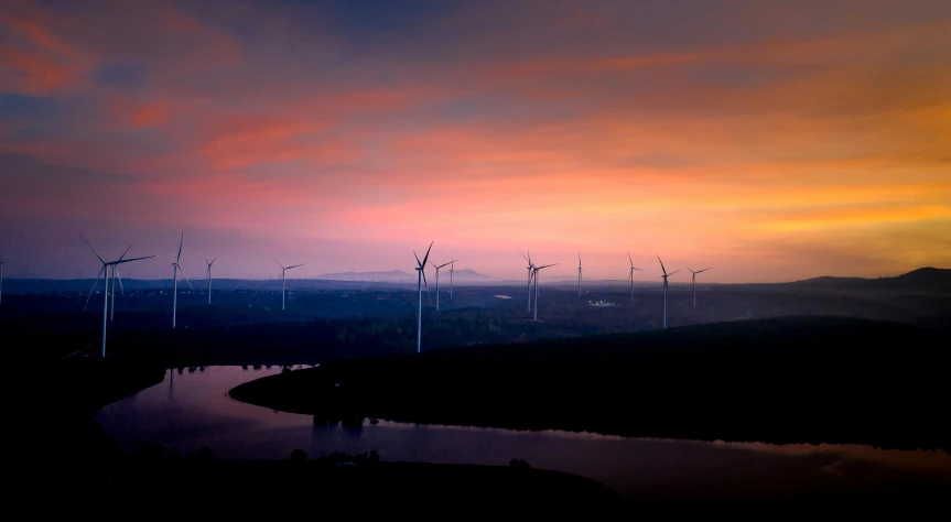 a bunch of wind mills are silhouetted against the sunset