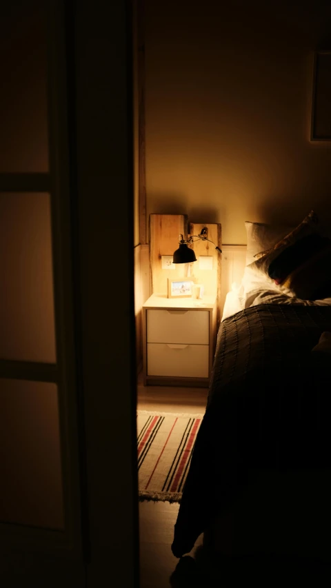 the lamp shines brightly on a dimly - lit bedroom