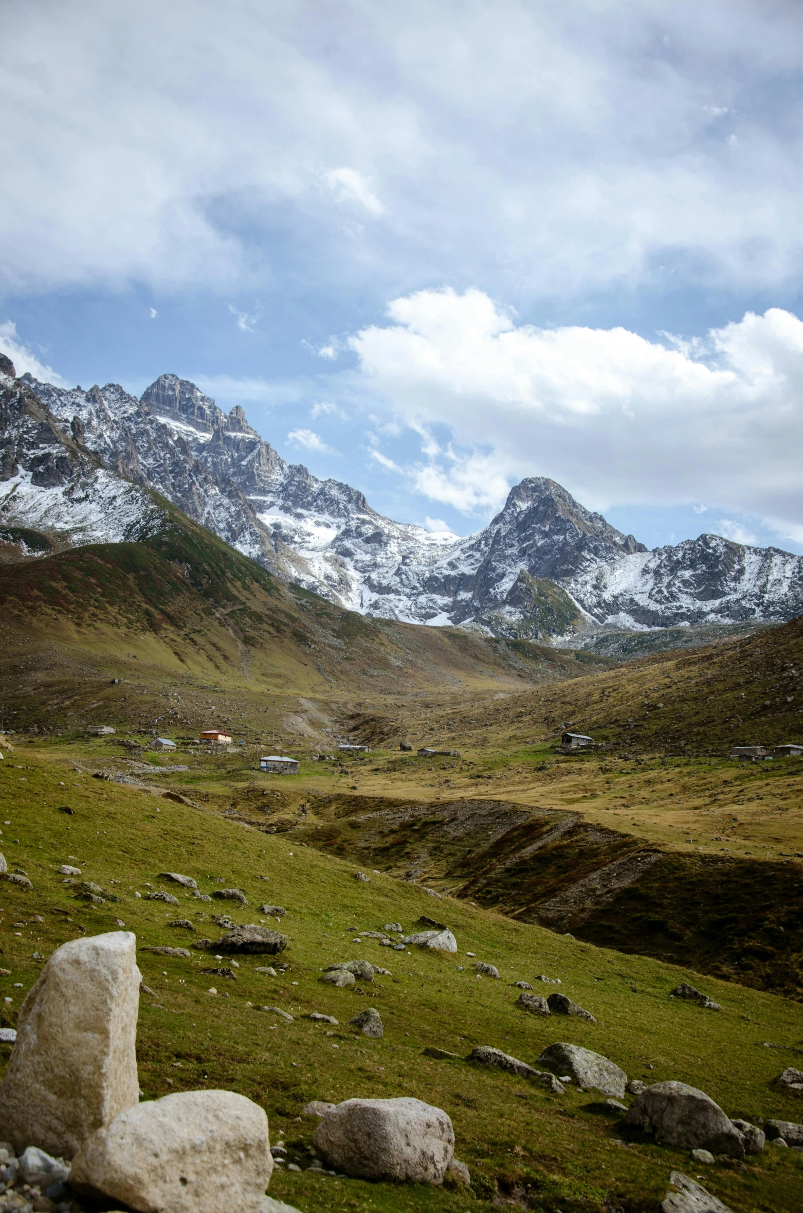 a grassy valley is seen with mountains in the background