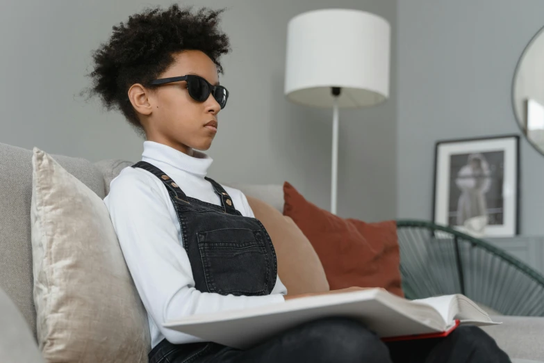 woman with large afro hair sitting on sofa reading a book