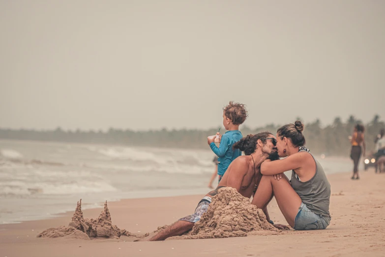 a group of people sit on the beach and hug