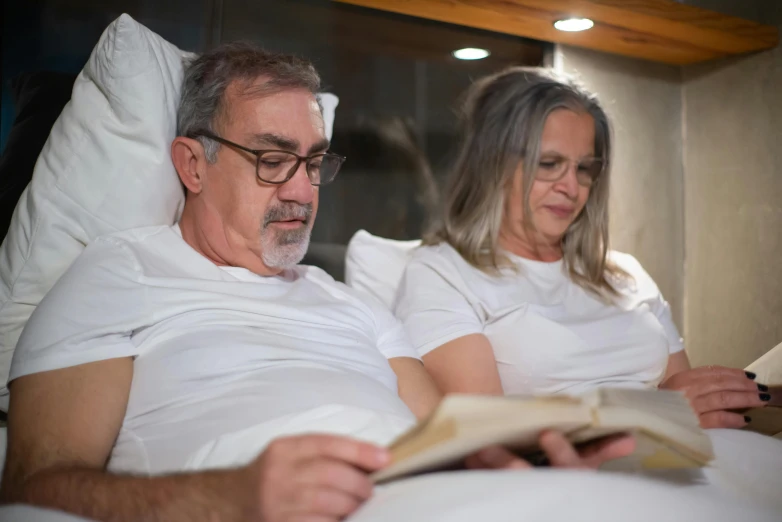 an older couple laying in bed while reading the book