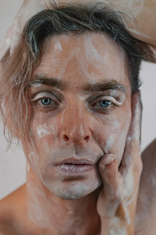 a man standing behind his face covered in white powder