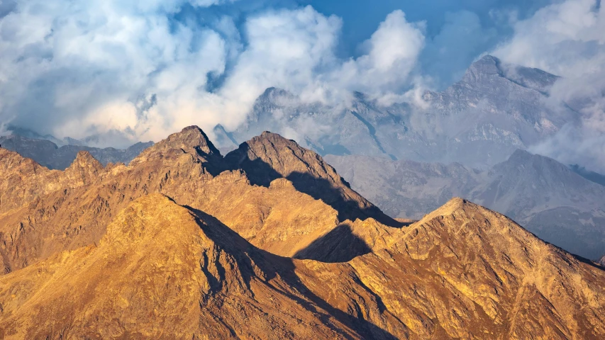 the view of a group of mountains against a cloudy sky