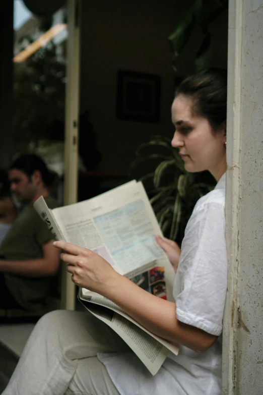 a woman with long brown hair sitting down while reading a book