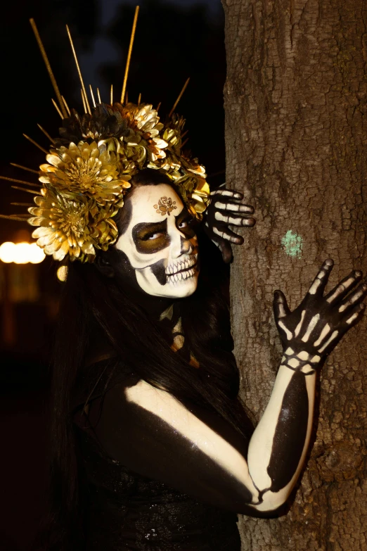 a woman in skeleton makeup and makeup is hugging a tree