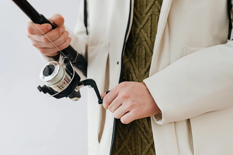 person in cream coat holding a black metal detector