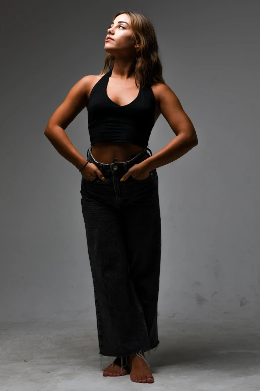 woman in cropped black top and wide leg jeans posing