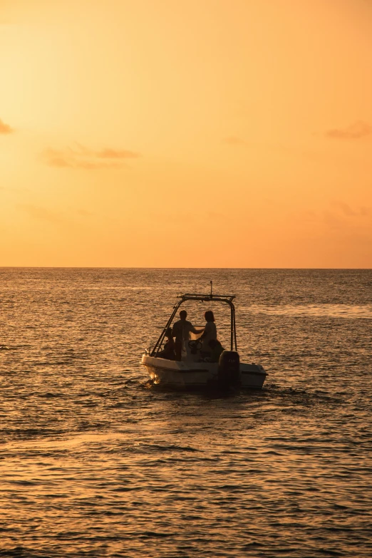 people are in the boat with the sun setting behind them