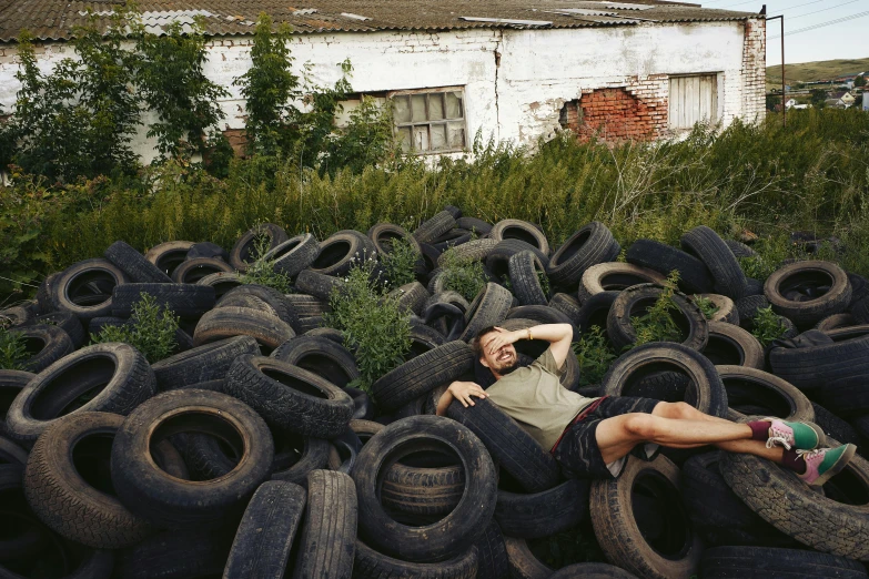 a woman in sunglasses laying on a large pile of tires