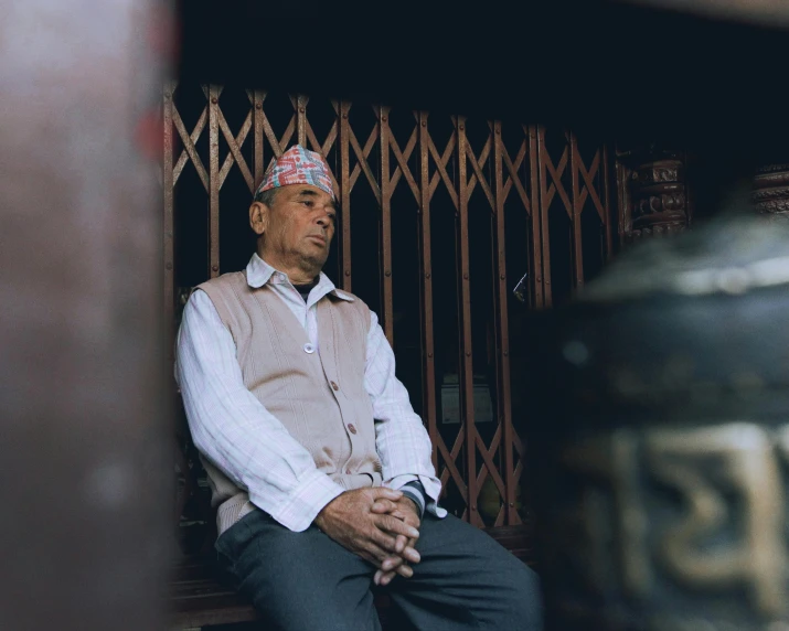 an elderly man in a suit is sitting on a ledge