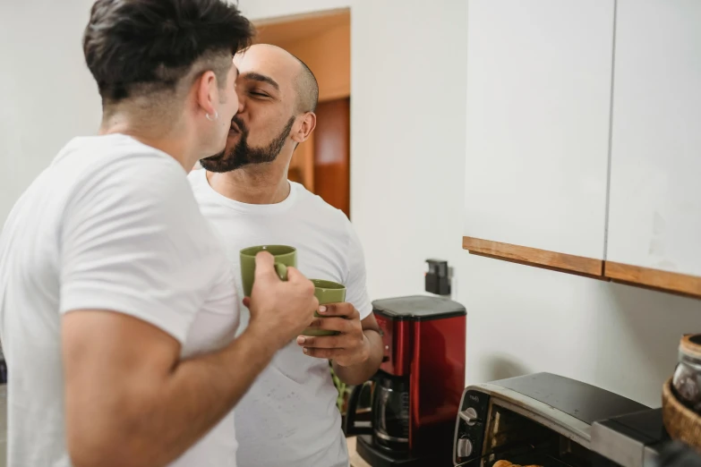 two males standing in front of a microwave while using their cell phones