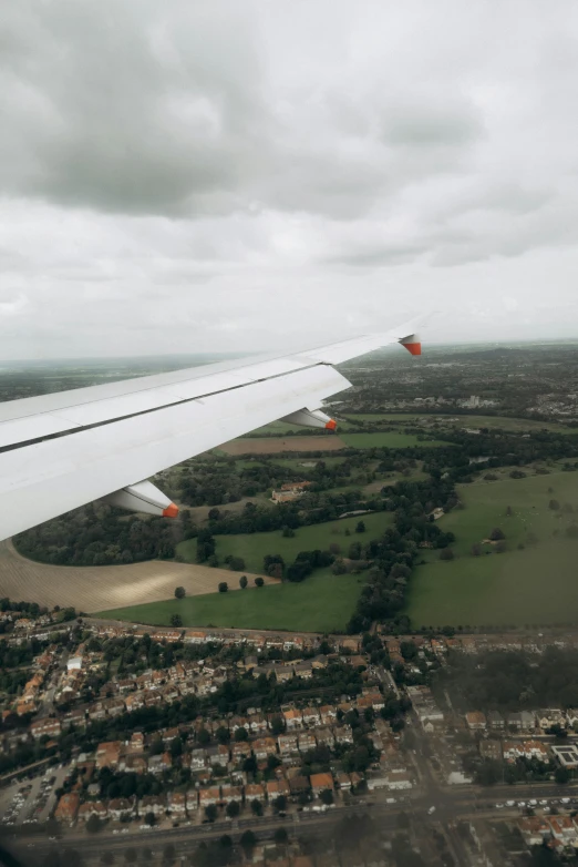 the wing of an airplane flying over a lush green field