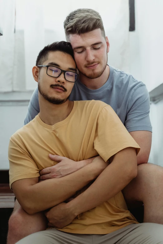 two young men hug with each other on a bench