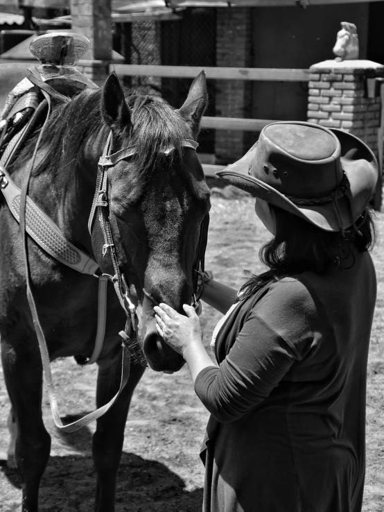 a woman wearing a hat putting her arm around a horse