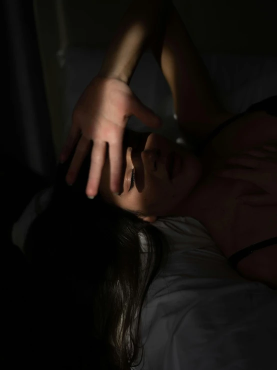 a woman is lying in bed with her hand near her face