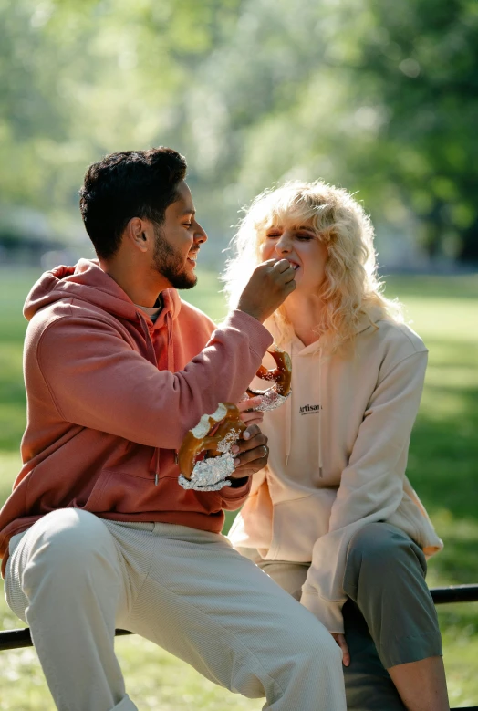 a man and woman eating on a bench in the park