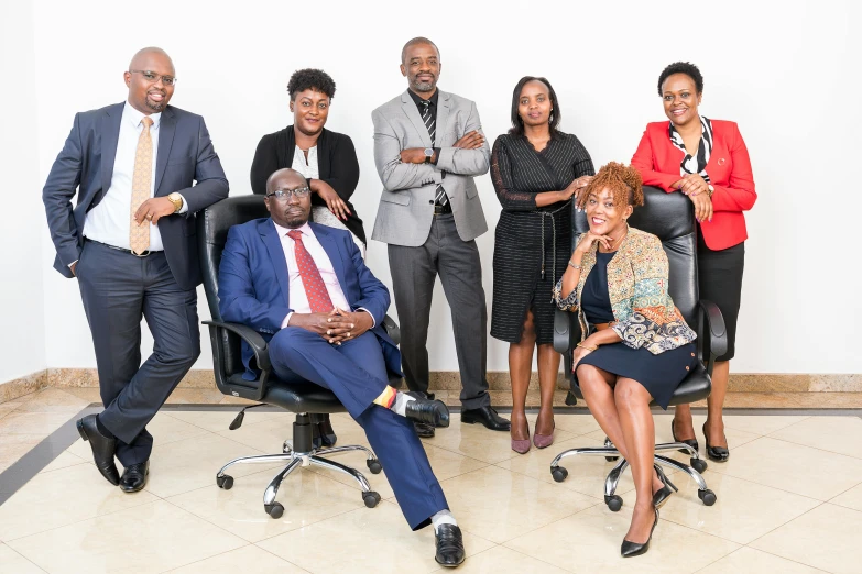 six people stand and smile in front of a white background