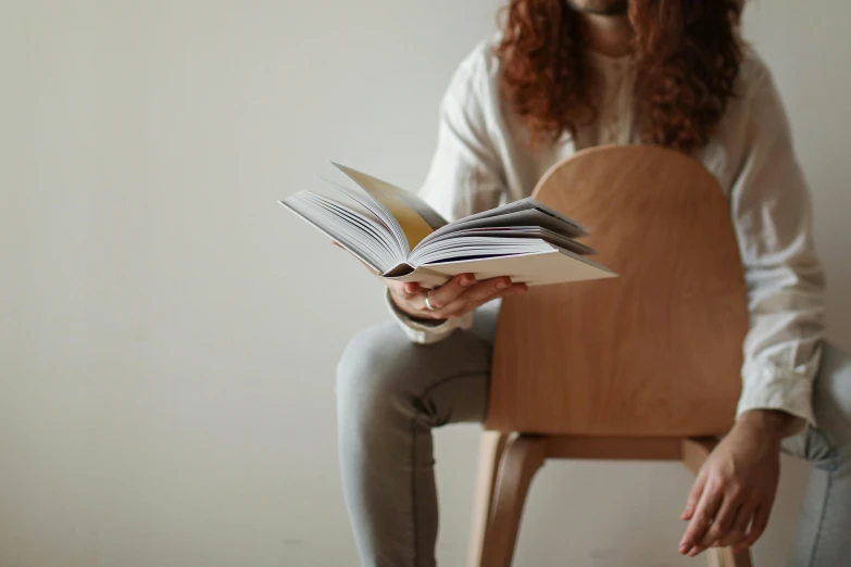 a woman sitting on a chair reading a book