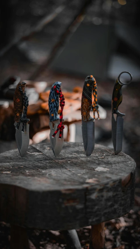 four knifes on a table with one black one white and one orange