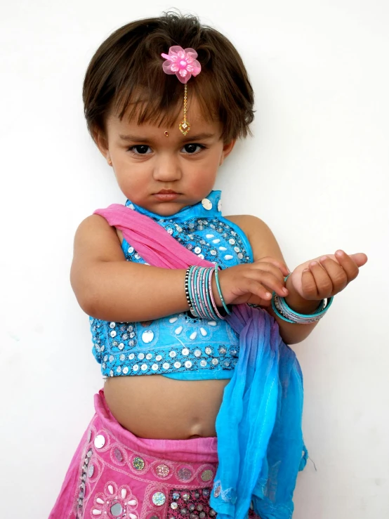 a little girl dressed in blue and pink standing