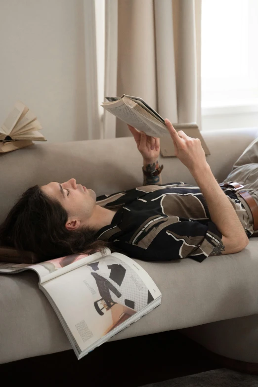 a man laying on the couch with a book