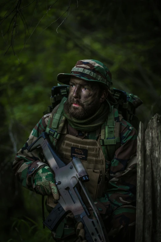 a man in camouflage holding a weapon and wearing his head covering