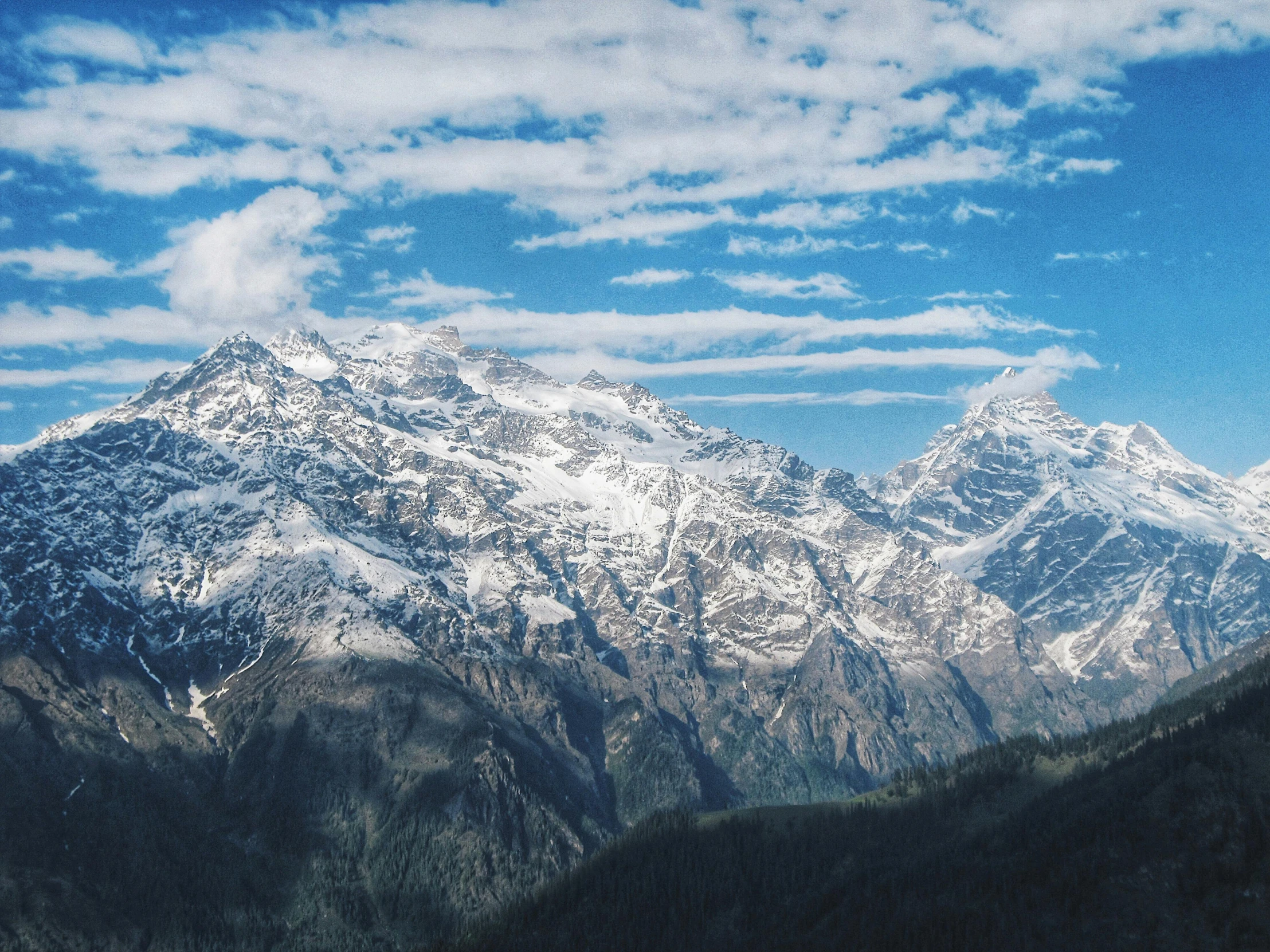 a mountain range under clouds and blue sky