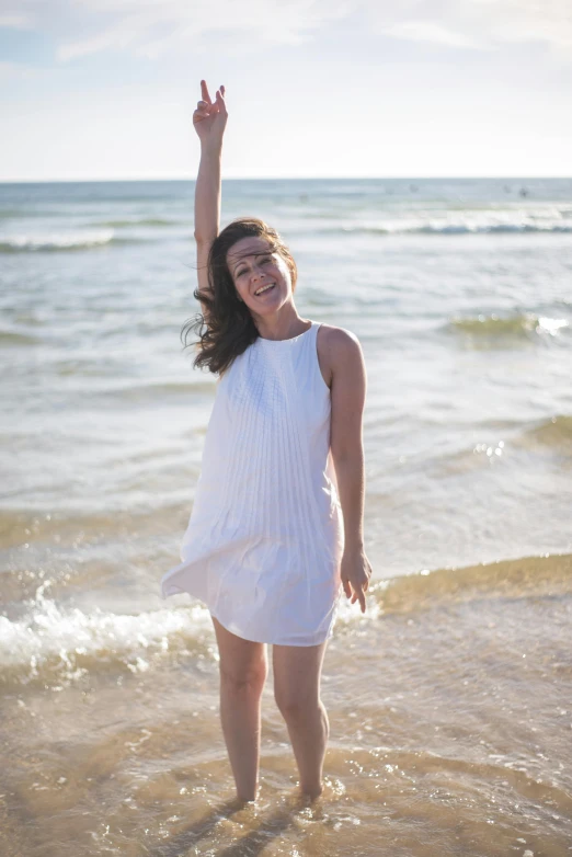 a woman stands in shallow water at the beach