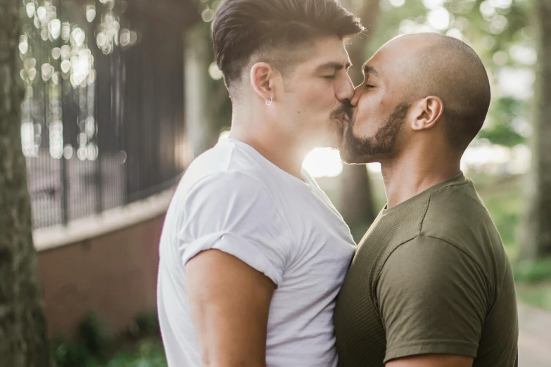 two men are standing close to each other kissing