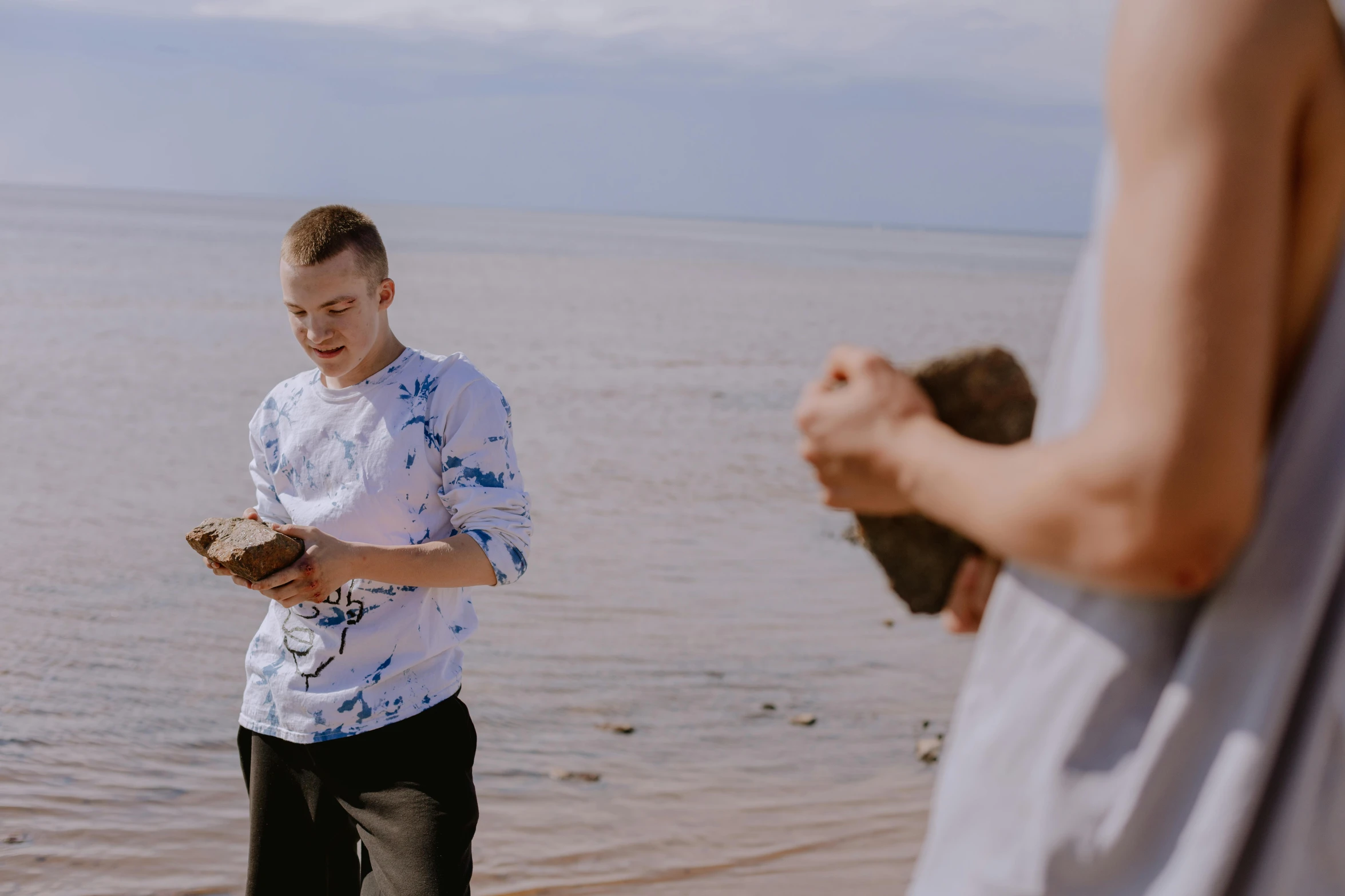 a man standing on the shore holding a wooden board