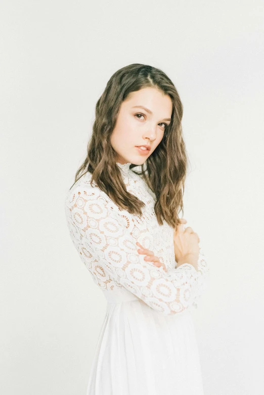 a woman standing with her arms folded on a white background