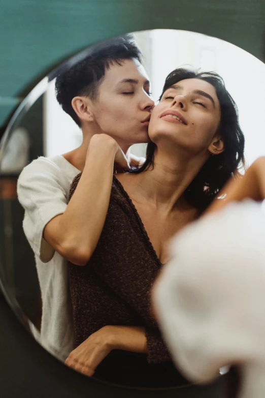 a man kissing a woman on the cheek in front of a mirror