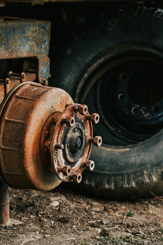 a old rusty car wheel and axles on a dirty field