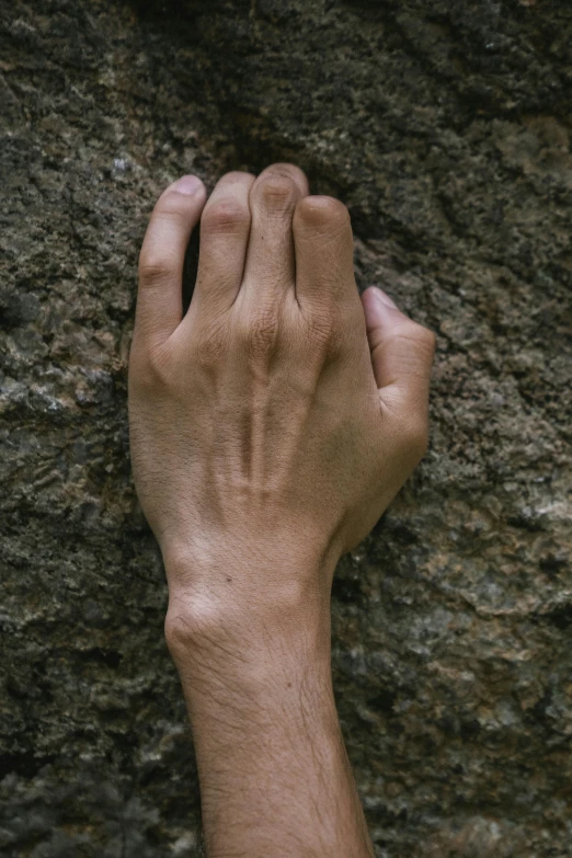 a persons hand resting on the side of a rock