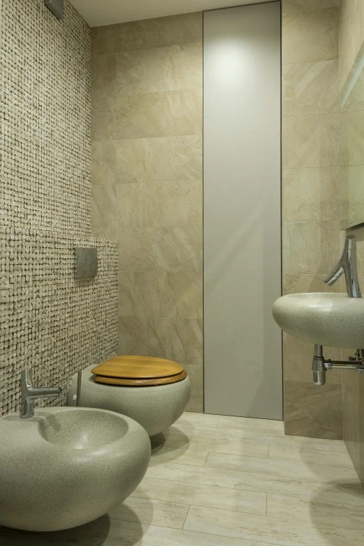 two round sinks in a bathroom with tan stone